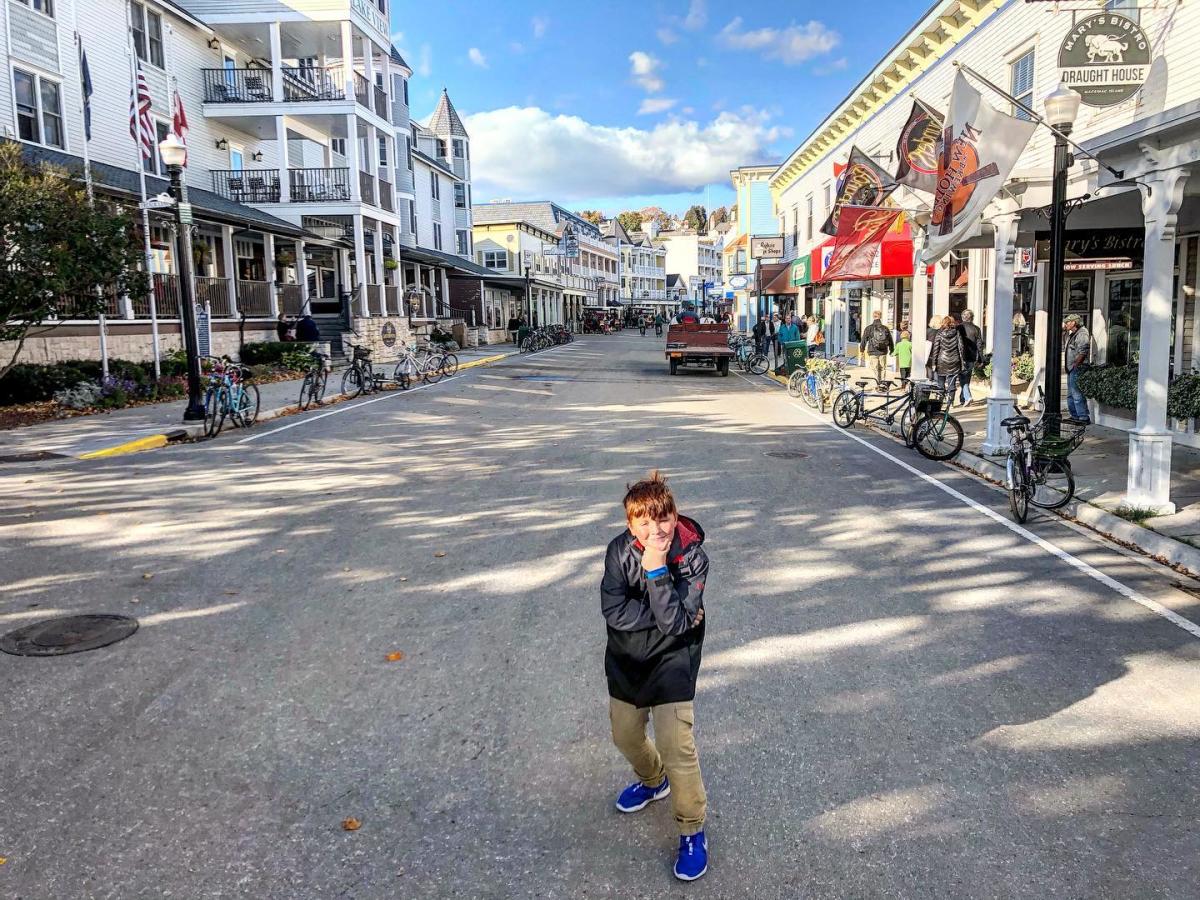 A pre-teen tween boy stands in the middle of Mackinac Island’s Main Street in the fall