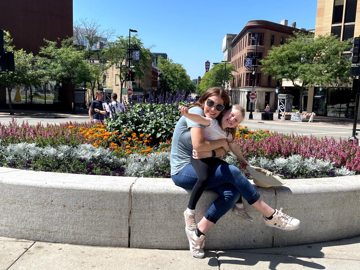 A woman and daughter pose by flowers at the Top of State Street