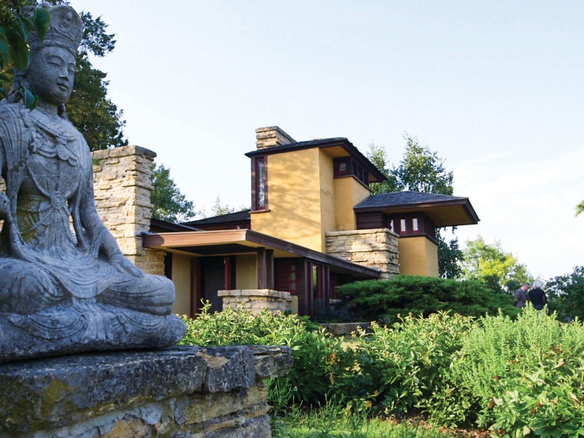 A statute sits outside of a Frank Lloyd Wright-designed building