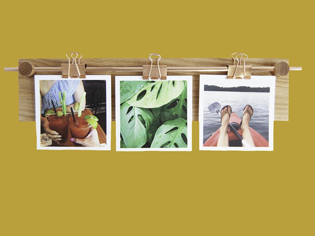 Polaroid photos hang from paper clips on a handcrafted item from Mad Makery