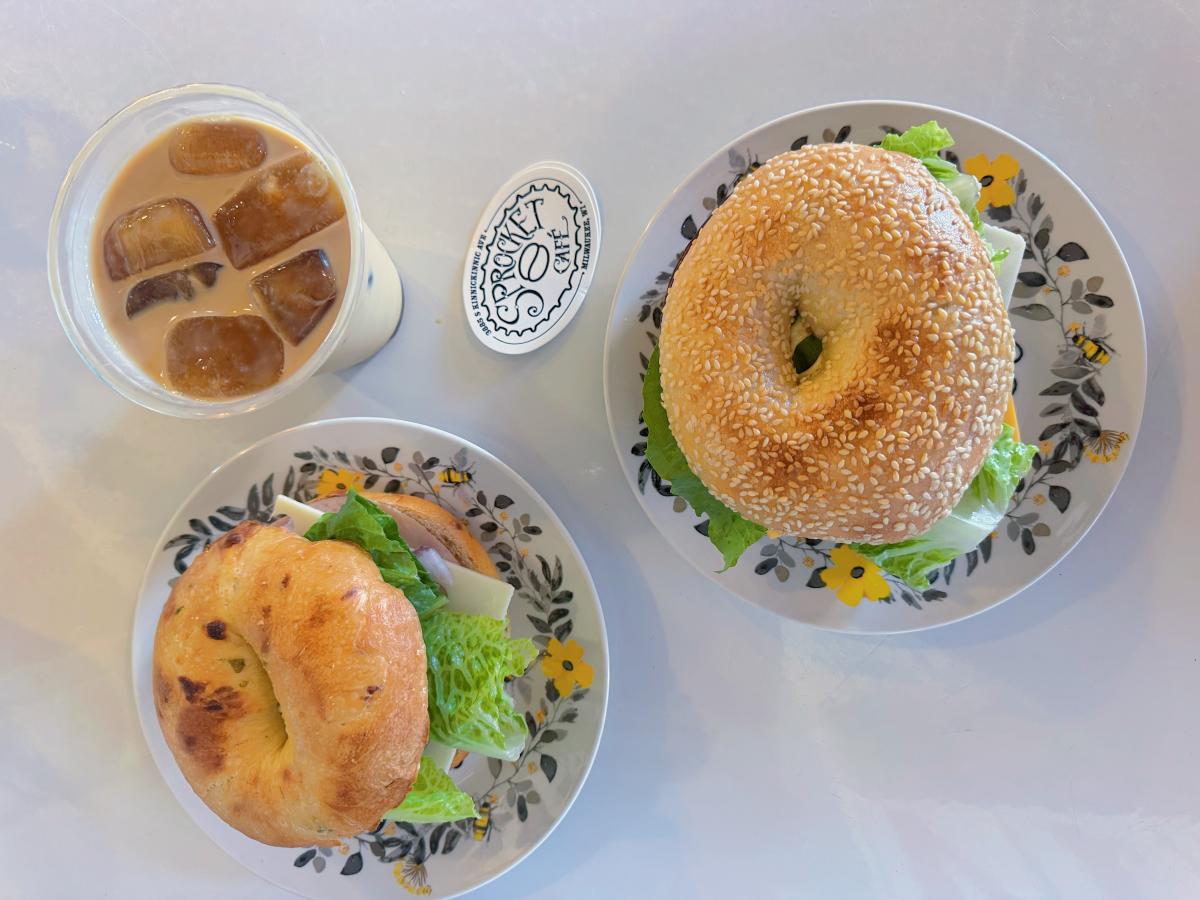 Two bagel sandwiches and an iced coffee sit on floral plates at Sprocket Cafe in Milwaukee.