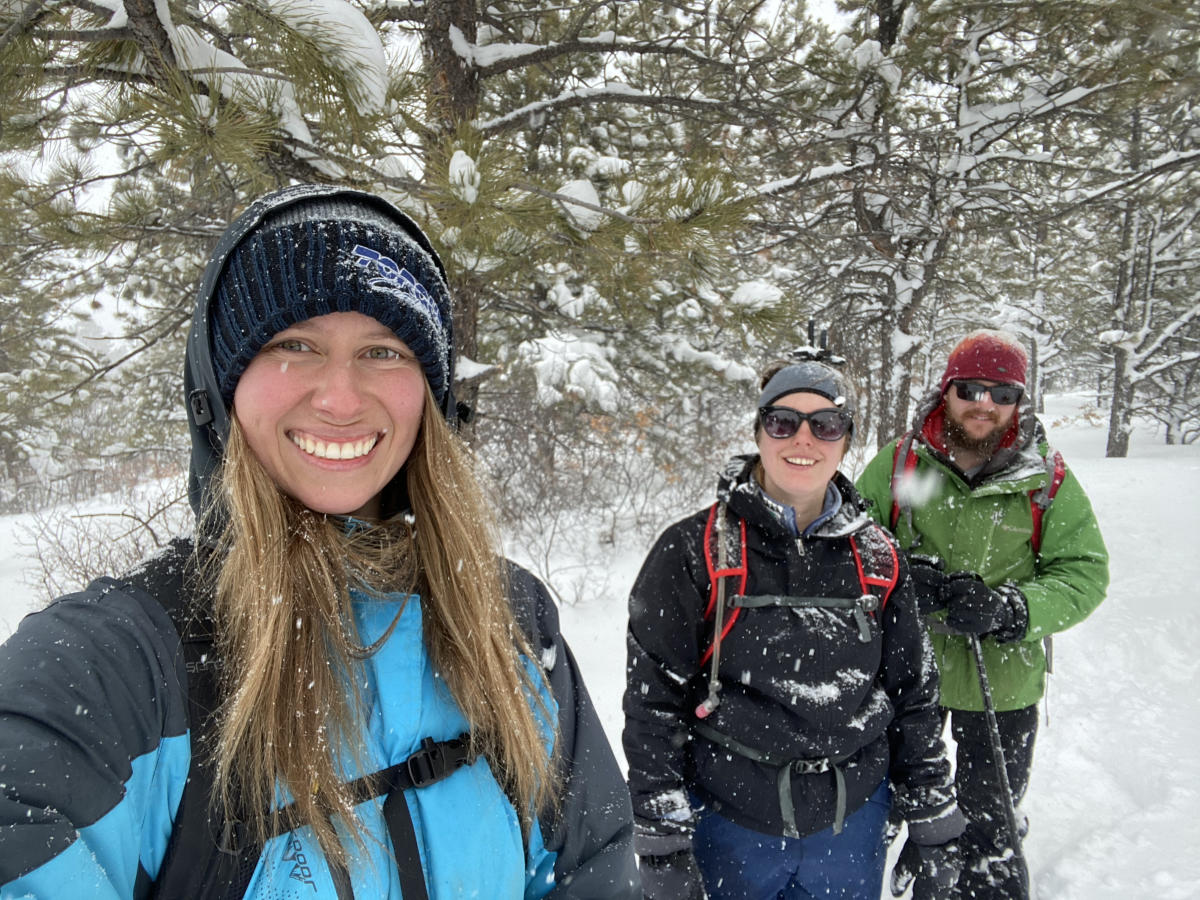 Three people standing next to each other in the snow