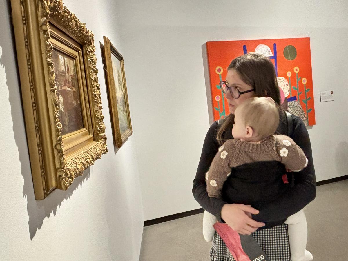 Woman holding baby looks at painting at Muskegon Museum of Art