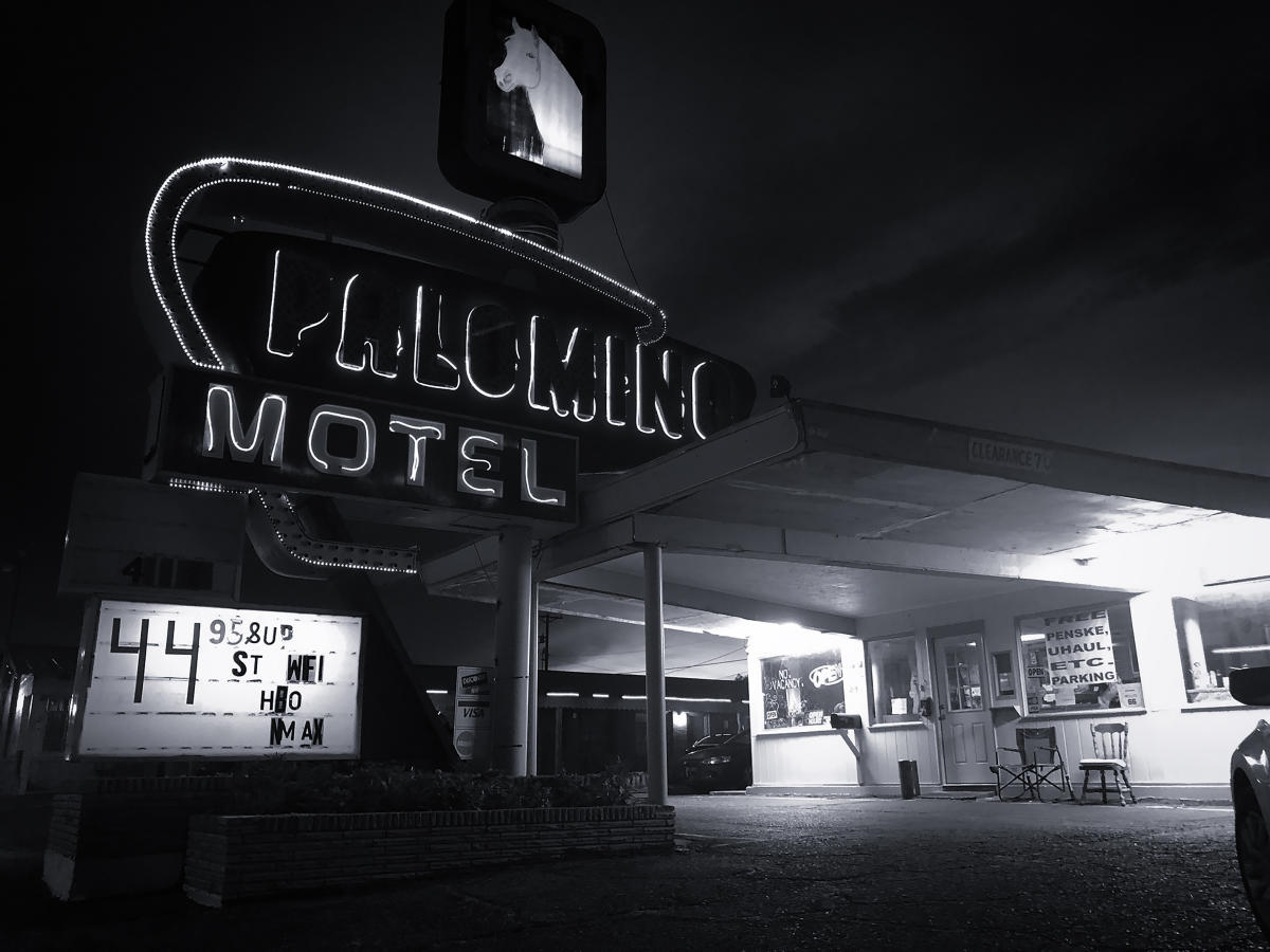 Black and white image of the vintage Palomino Motel at night, with neon signs.