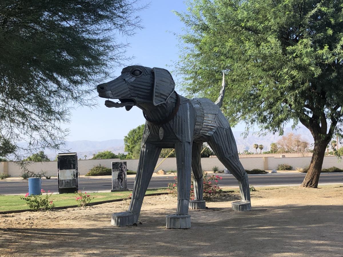 A 12-foot tall sculpture of a dog made of steel and recycled corrugated tin stands at the corner of Hjorth Park in Indio.
