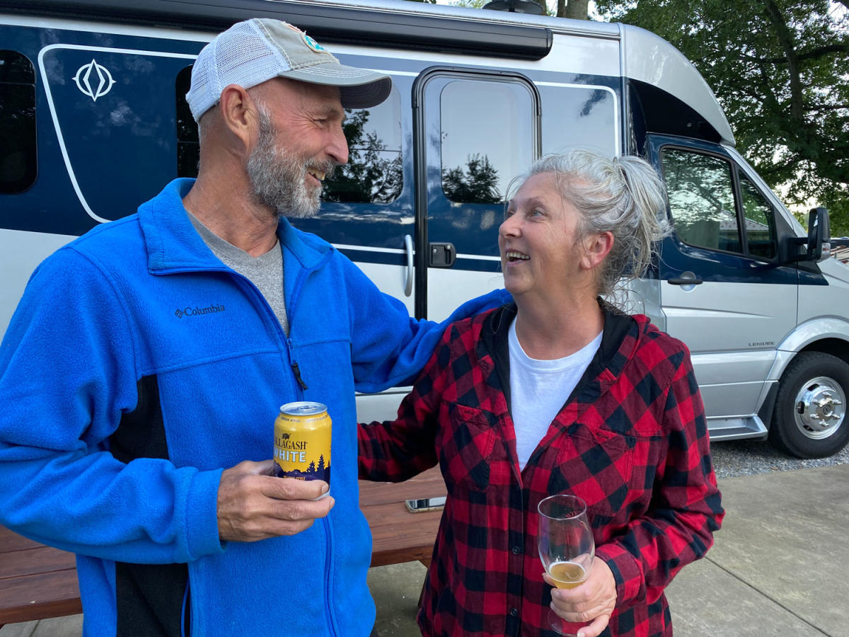 couple cheering, RV behind parked