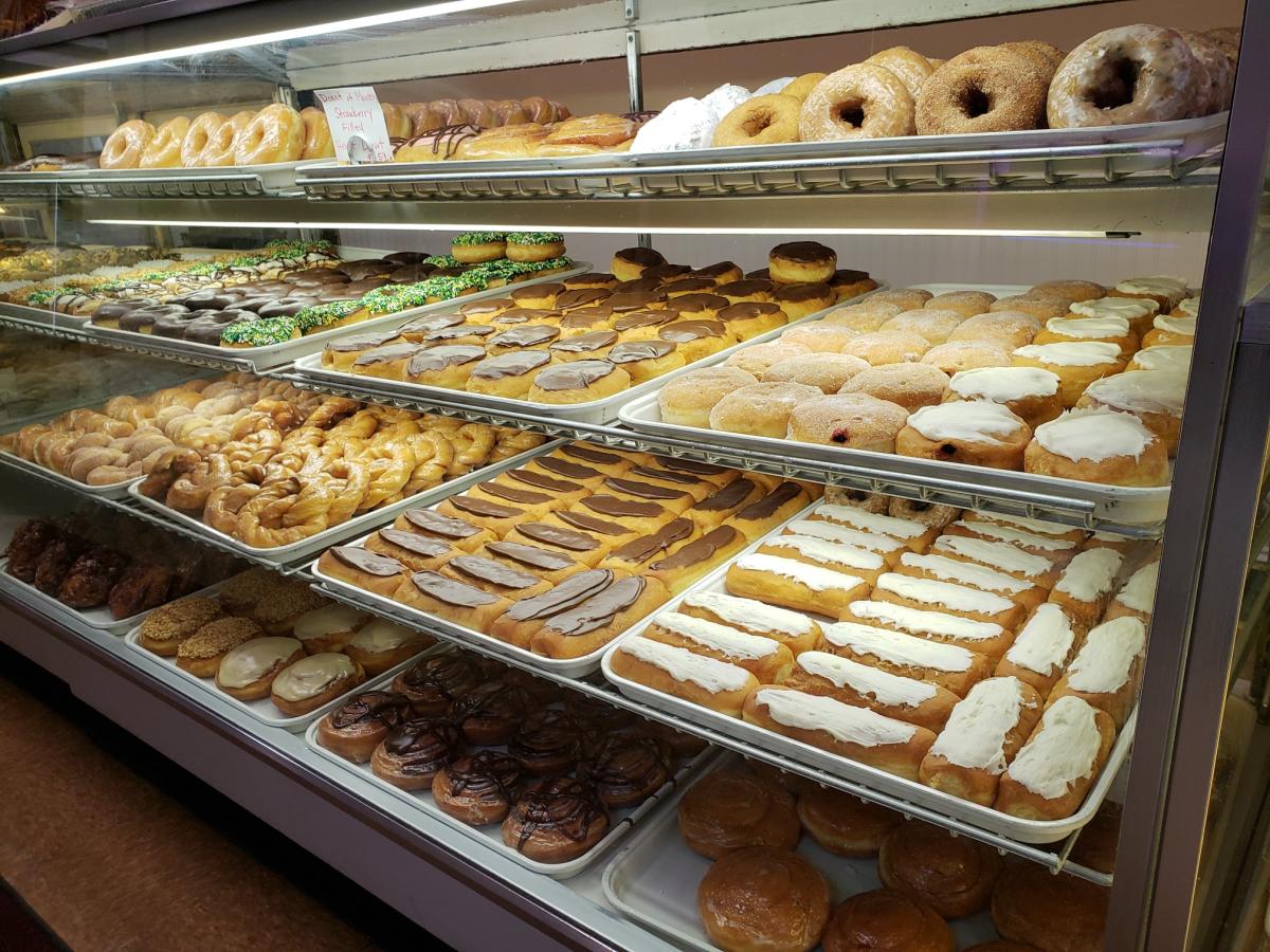 A glass case is filled with shelves of different types of donuts.