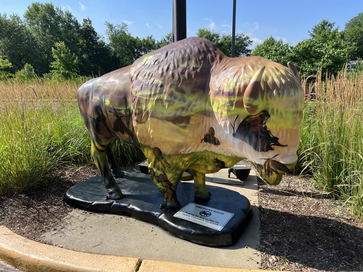 A bison statue is spray painted with a landscape