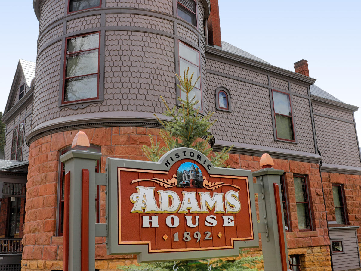 An exterior shot of the Adams House Museum in Deadwood, a two-story red brick Queen Anne Victorian style house.