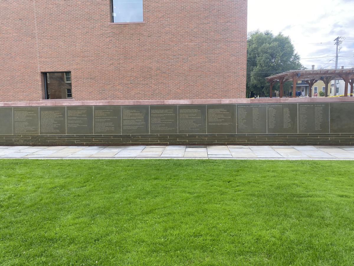 stone wall with water running down the front behind green grass