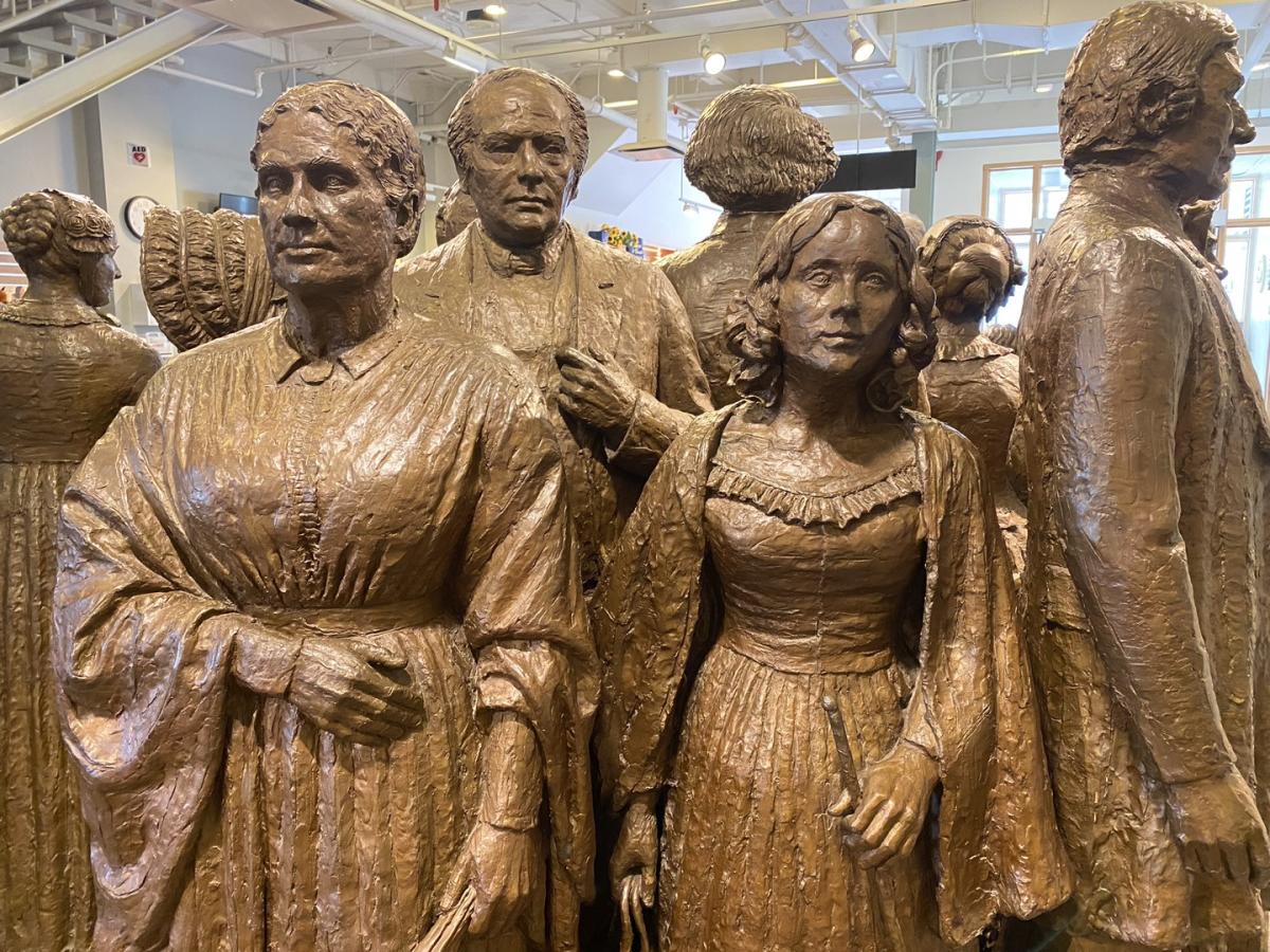 bronze statues of men and women standing around