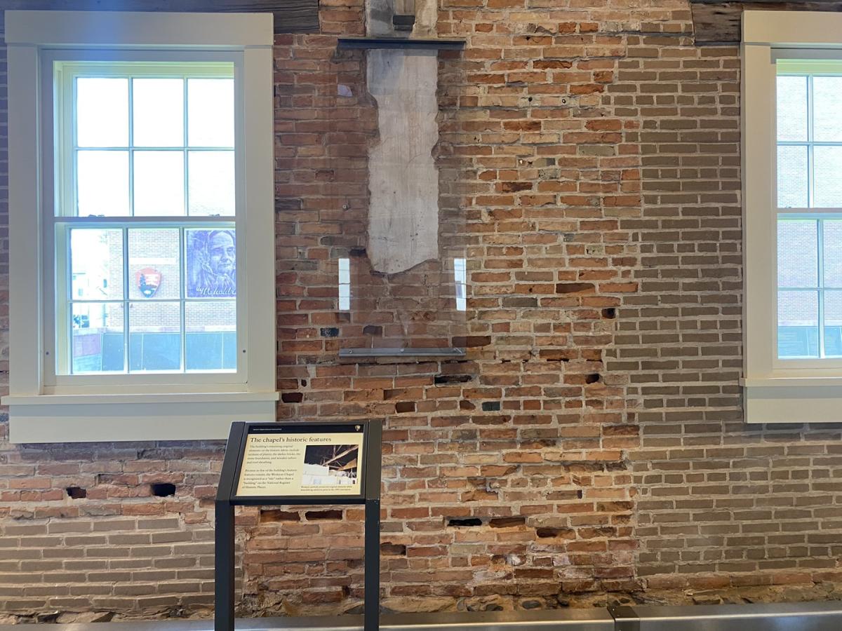 Wesleyan Chapel original wall behind glass frame against brick walls