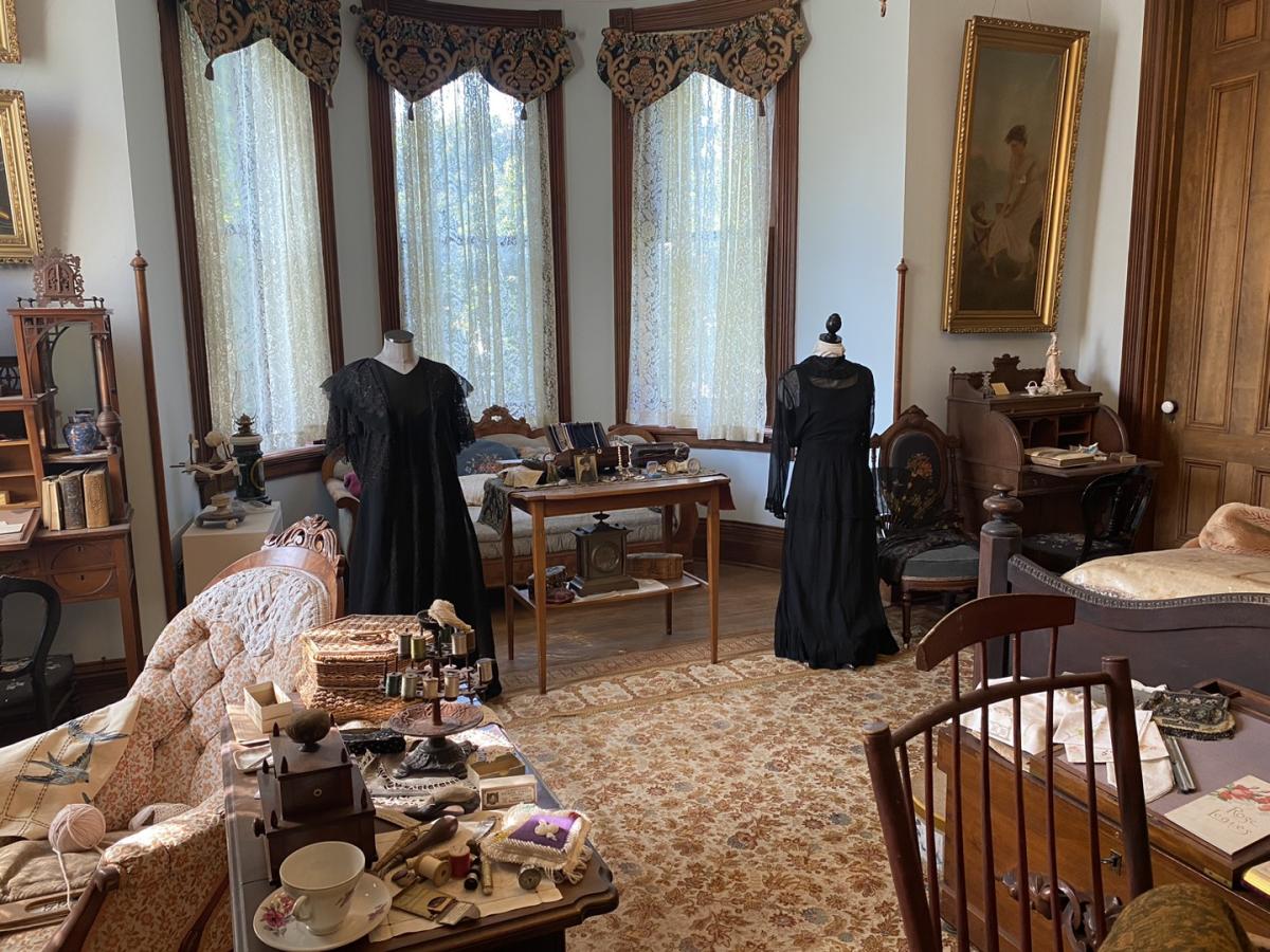 victorian bedroom with mannequins in black dresses standing in the middle of the colorful room