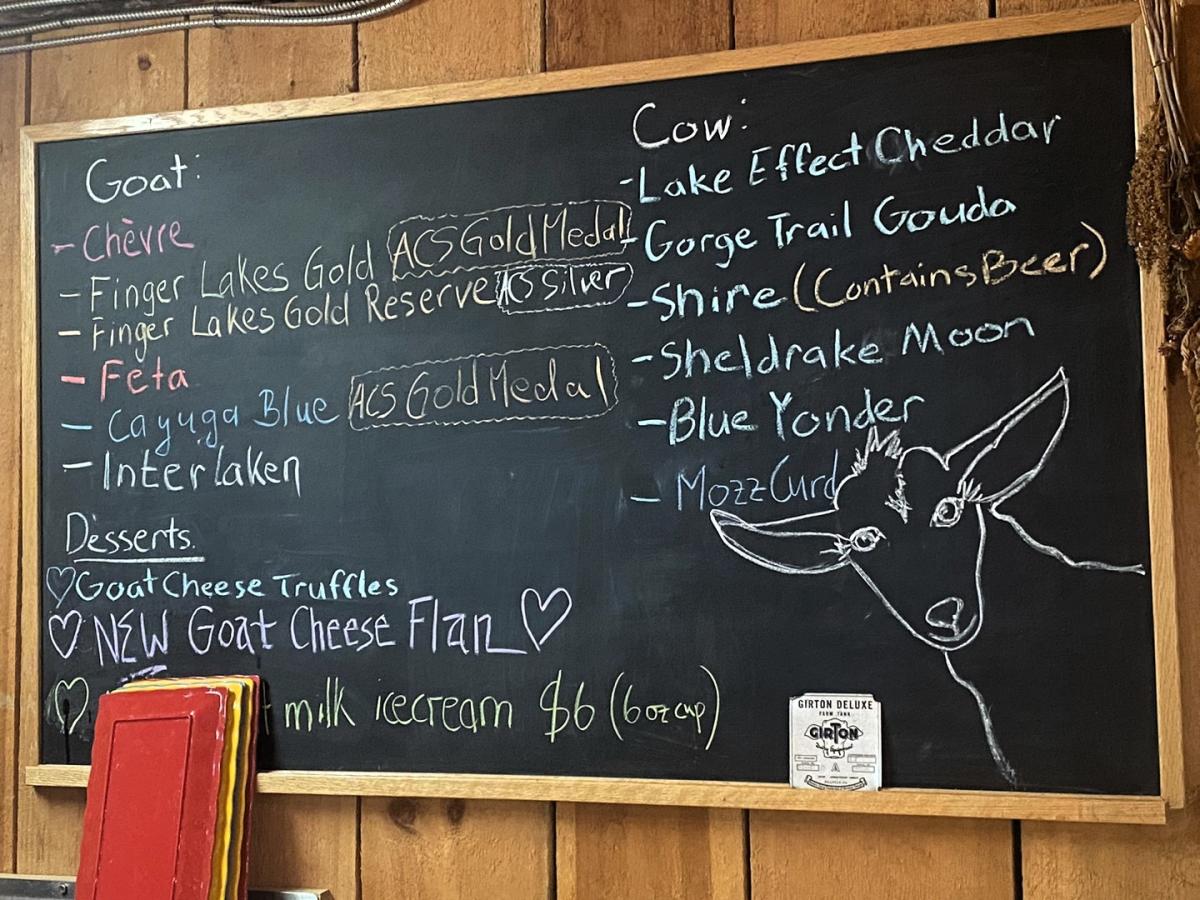 Cheese menu written on a black chalkboard with a cartoon goat in the corner