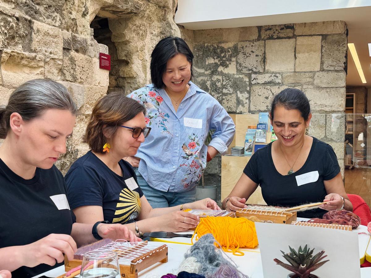 Group of women weaving on small looms at God's House Tower as part of a women led workshop