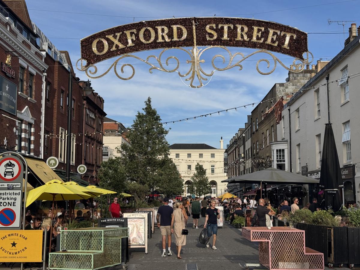 Oxford Street filled with people enjoying the sunny weather, with many having drinks and meals at outdoor terraces