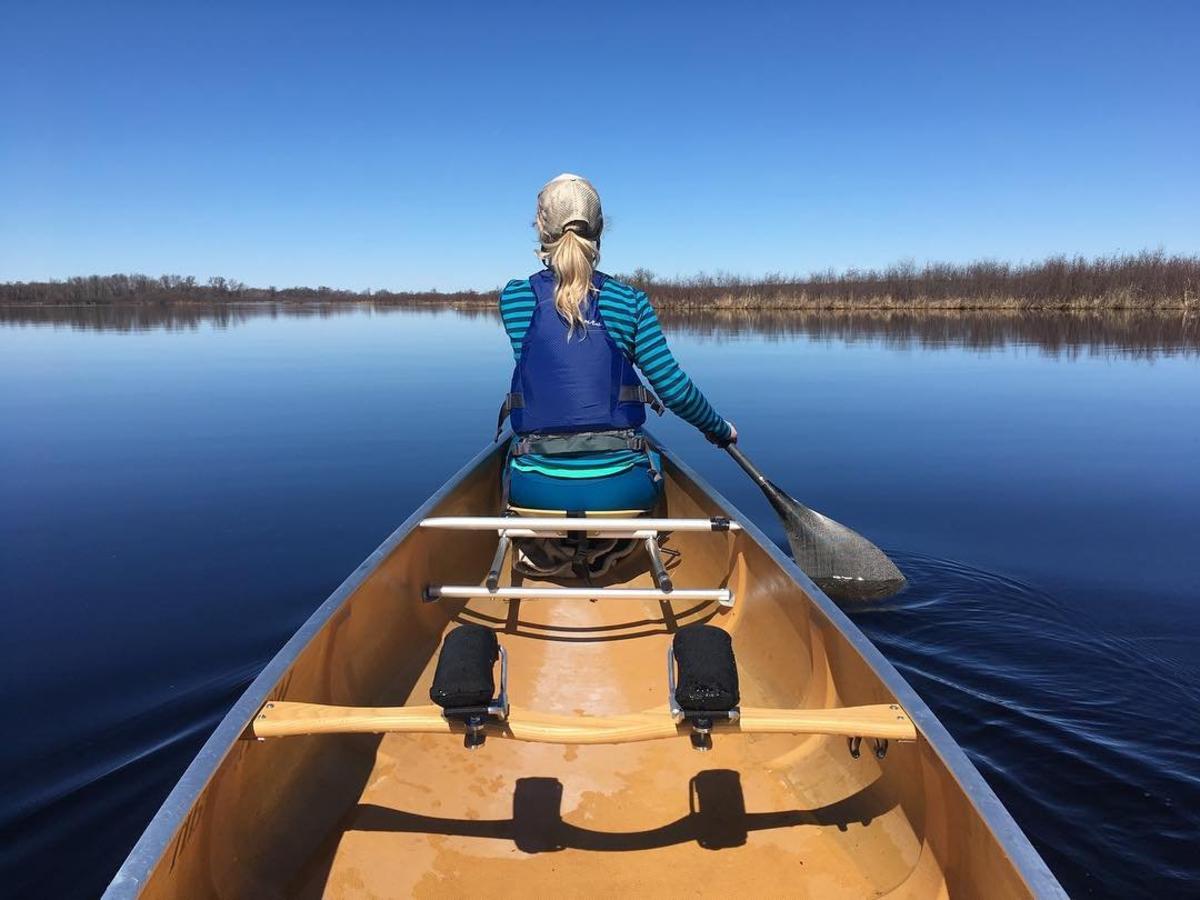 A woman canoes across quiet water in the Stevens Point Area.