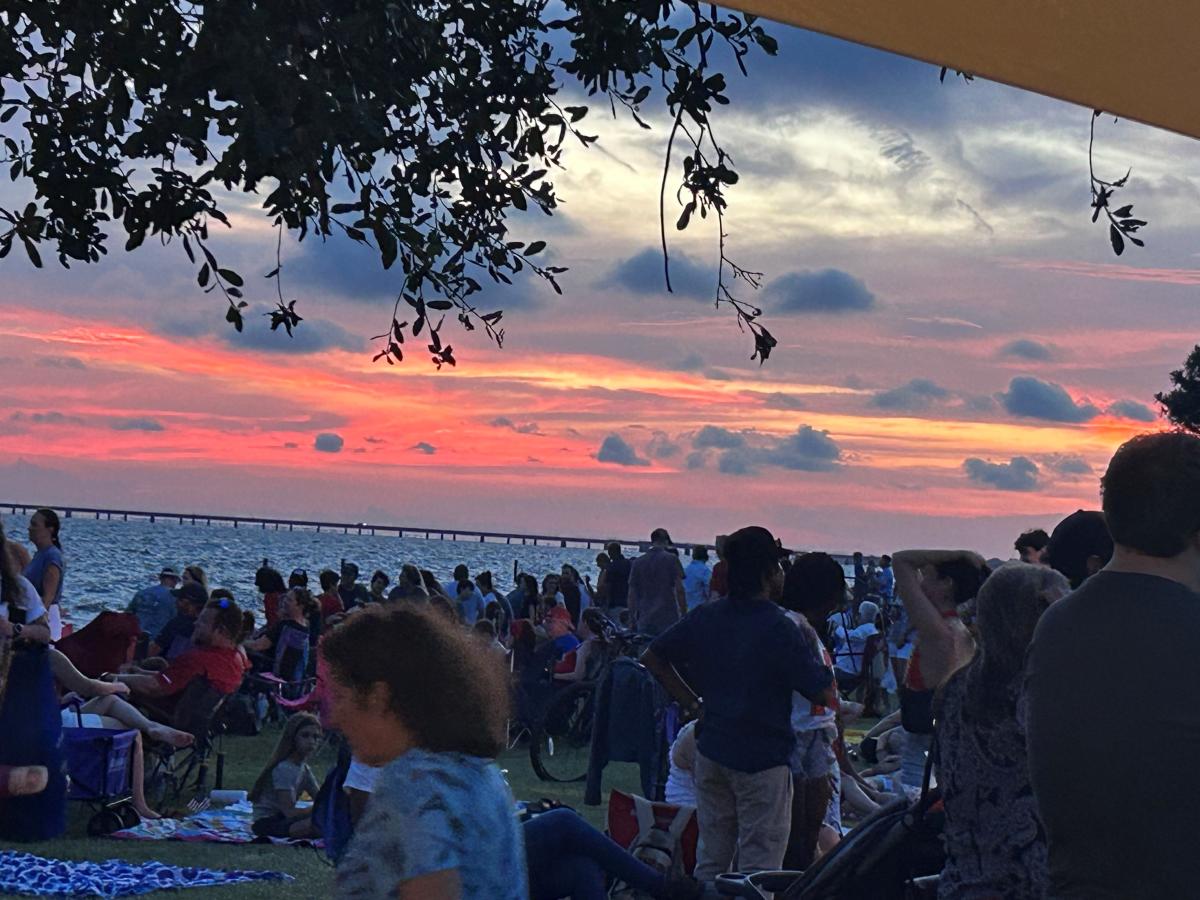 Crowds gathered at the Mandeville lakefront with a sunset view behind.