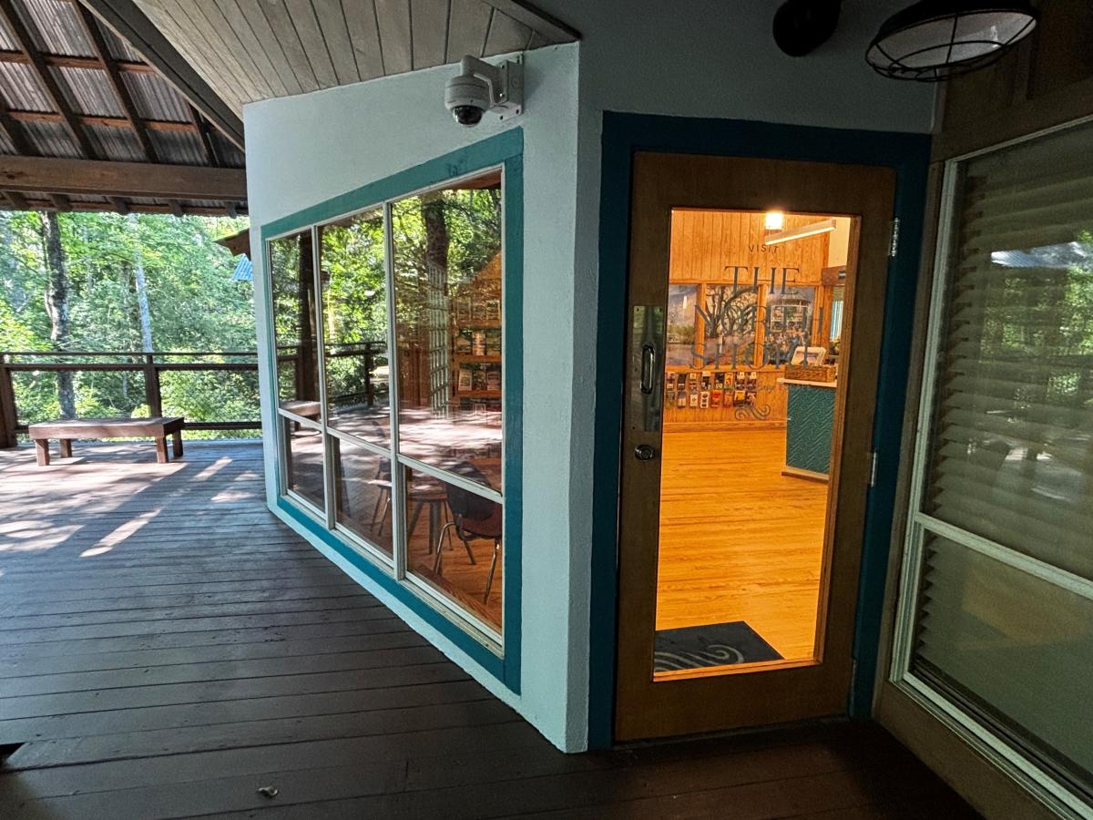 The front entrance to the Visit The Northshore Visitor Center opens from a shaded wooden deck surrounded by forest views and large windows.