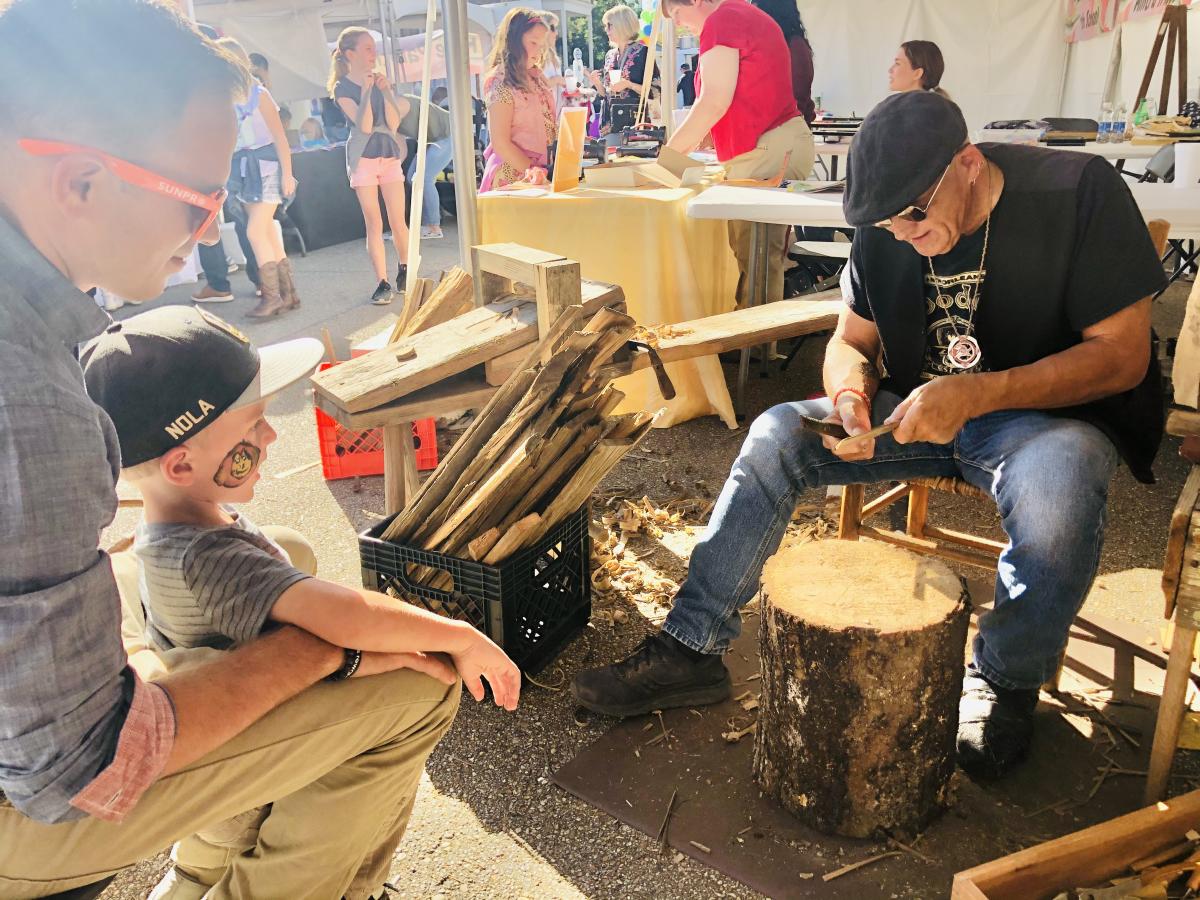 Grayhawk Perkins demonstrates traditional wood shaving as visitors watch at the Covington Three Rivers Art Festival.