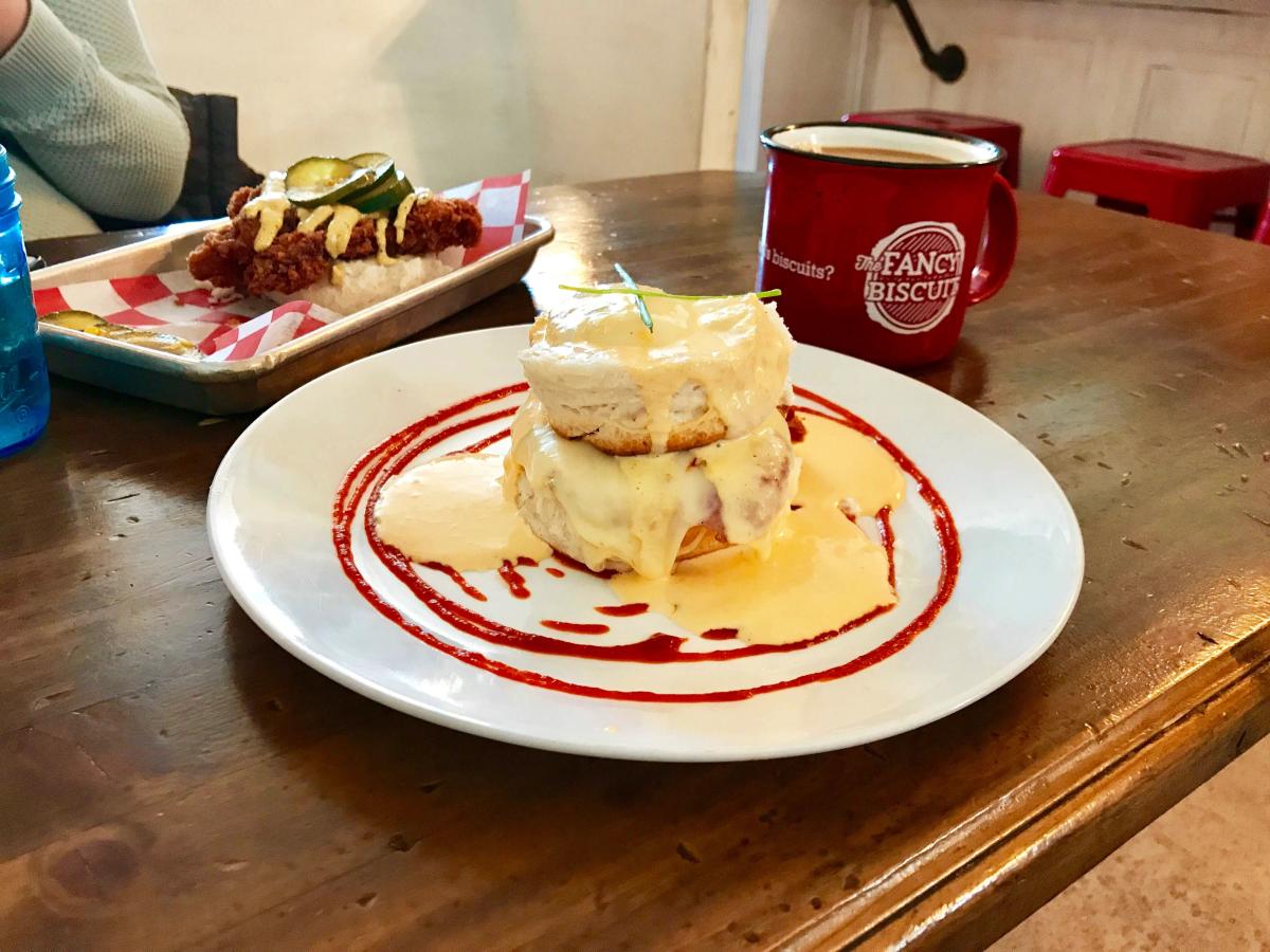 Biscuit on a plate with sriracha smothered in gravy with coffee in the background