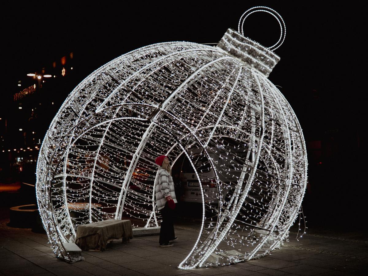 Kvinne står i en stor julekule av lys