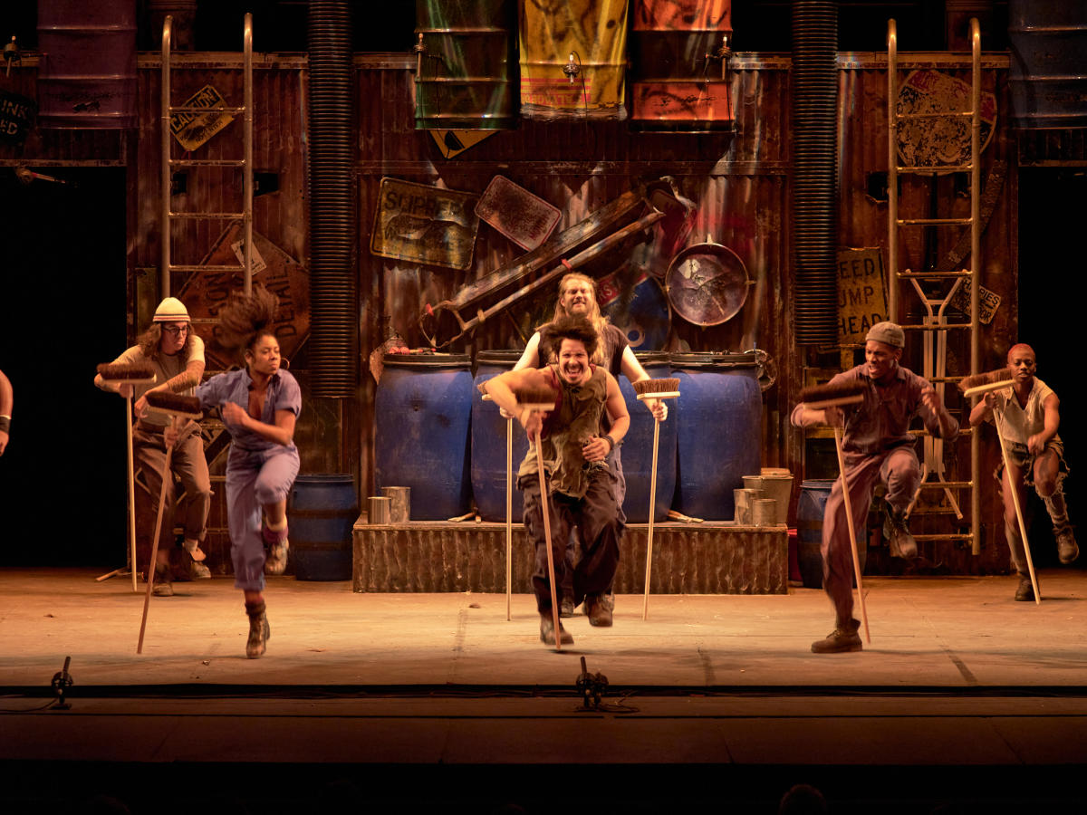 People play using brooms at a performance of "Stomp!"