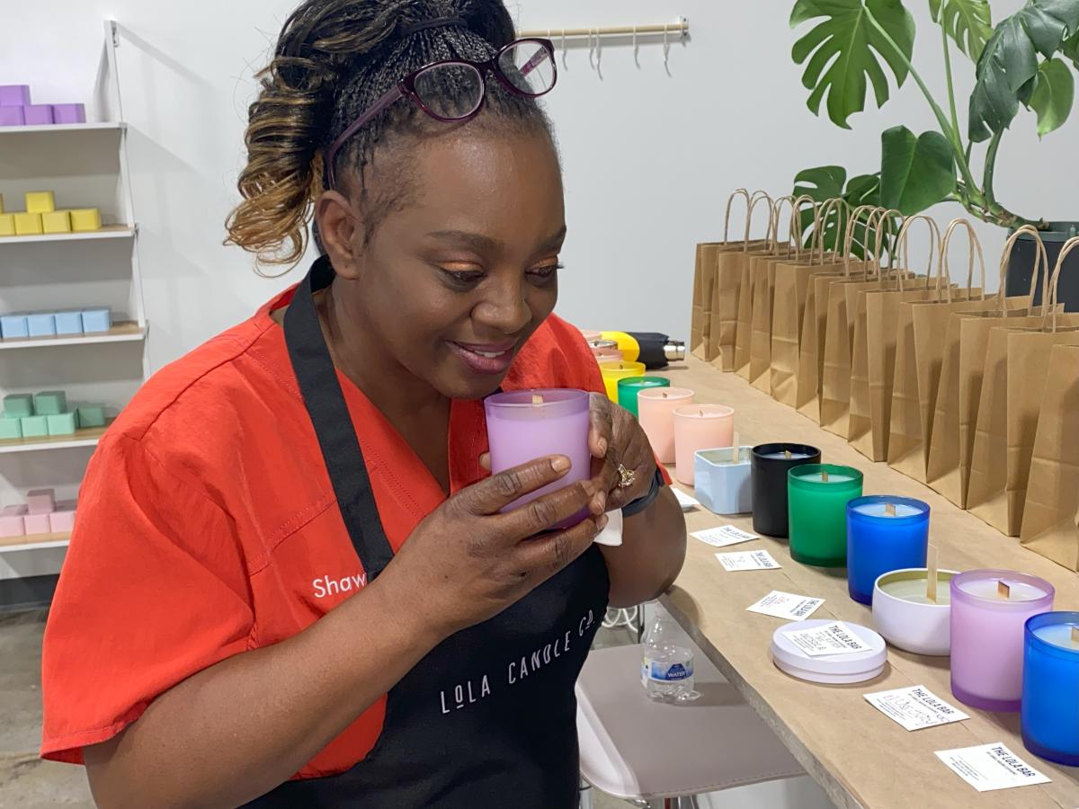 The owner of Lola Candle Co. smiles while smelling a candle