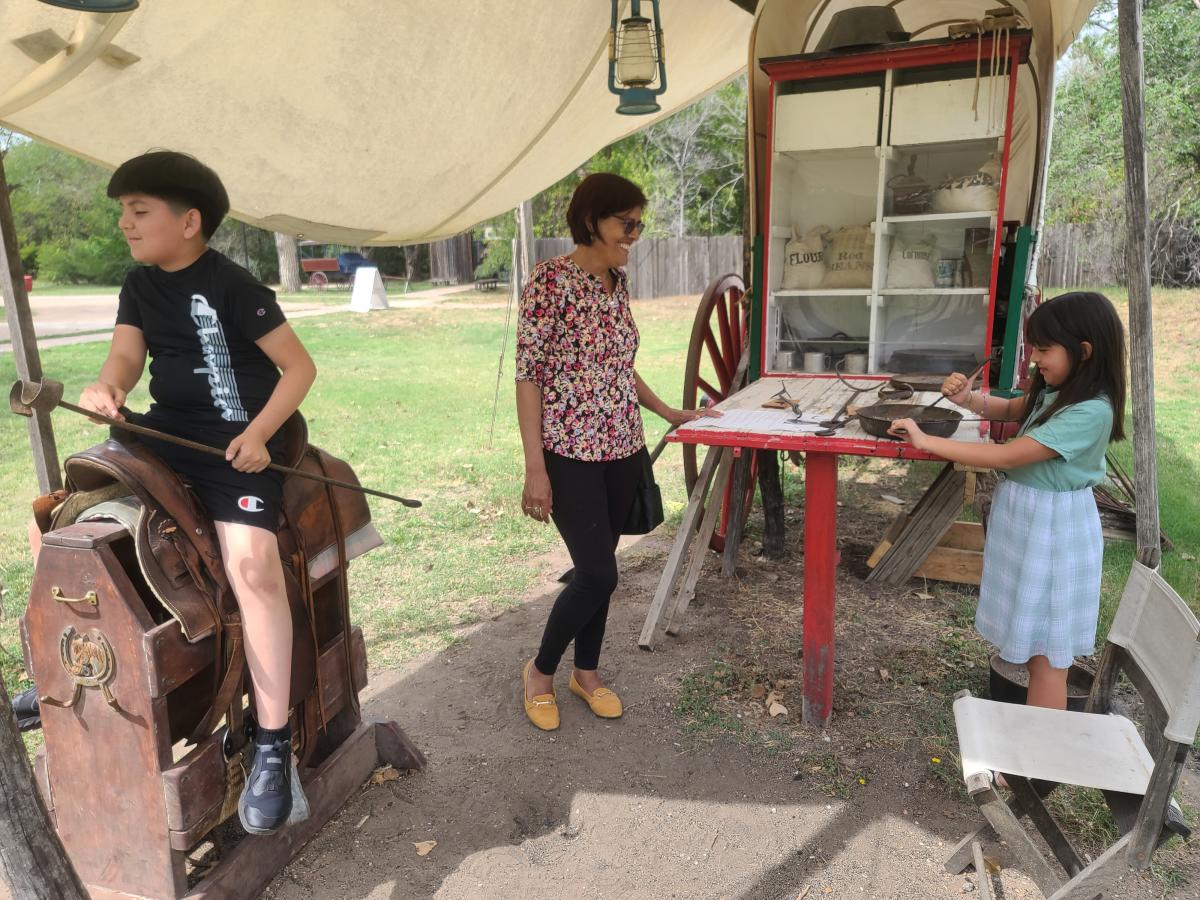 A woman, boy and girl play at an exhibit at Old Cowtown Museum