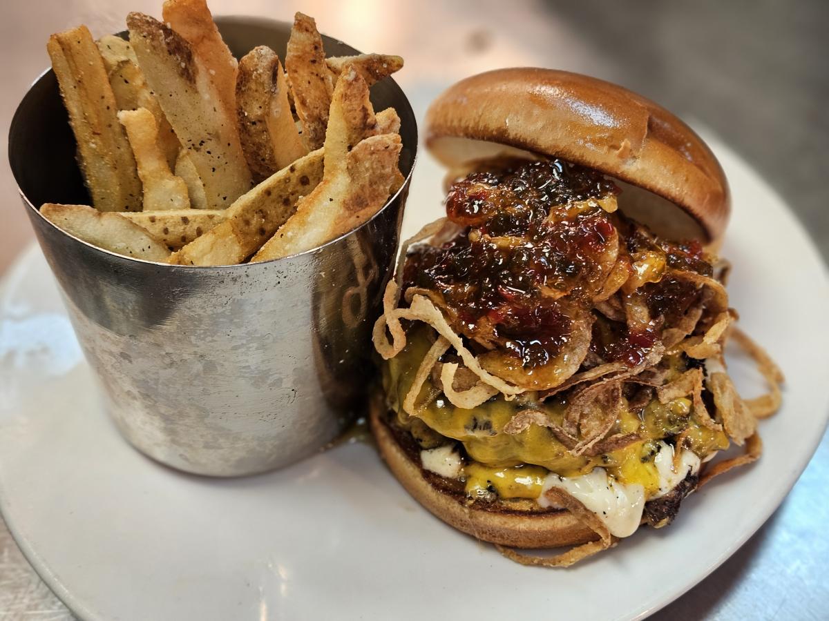 A burger is served with cheese,  jam and fried onions with fries at River City Brewing Co.