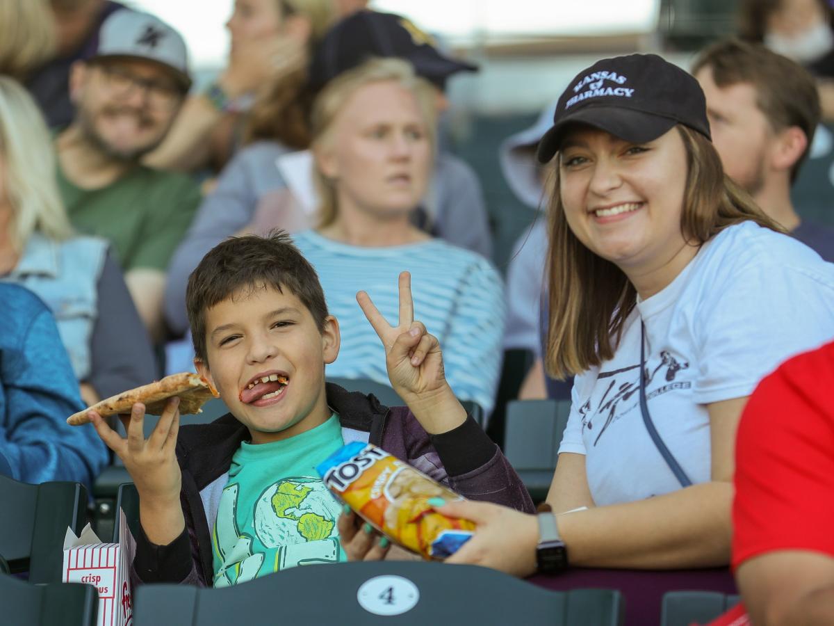 A young woman and small boy pose smiling for the camera while at a Wind Surge game