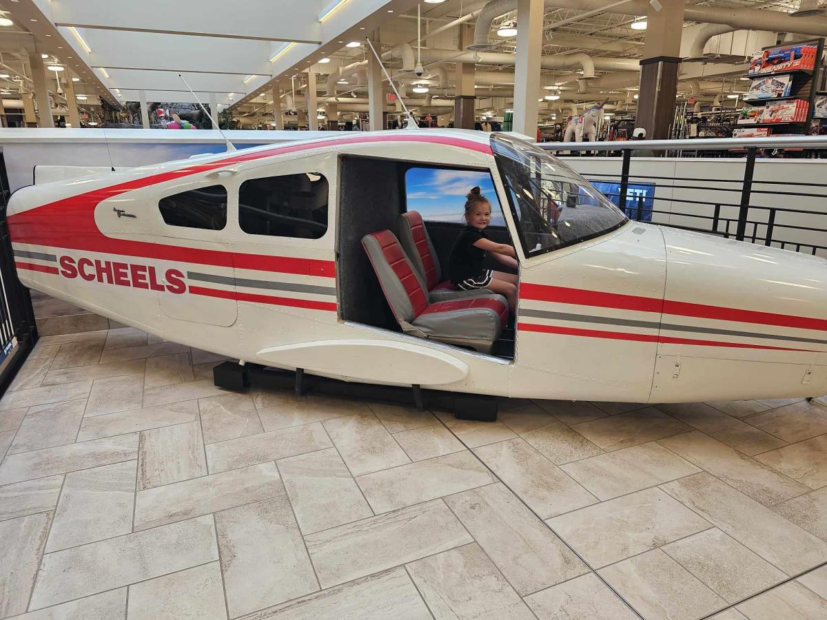 A young girl plays on an airplane inside SCHEELS