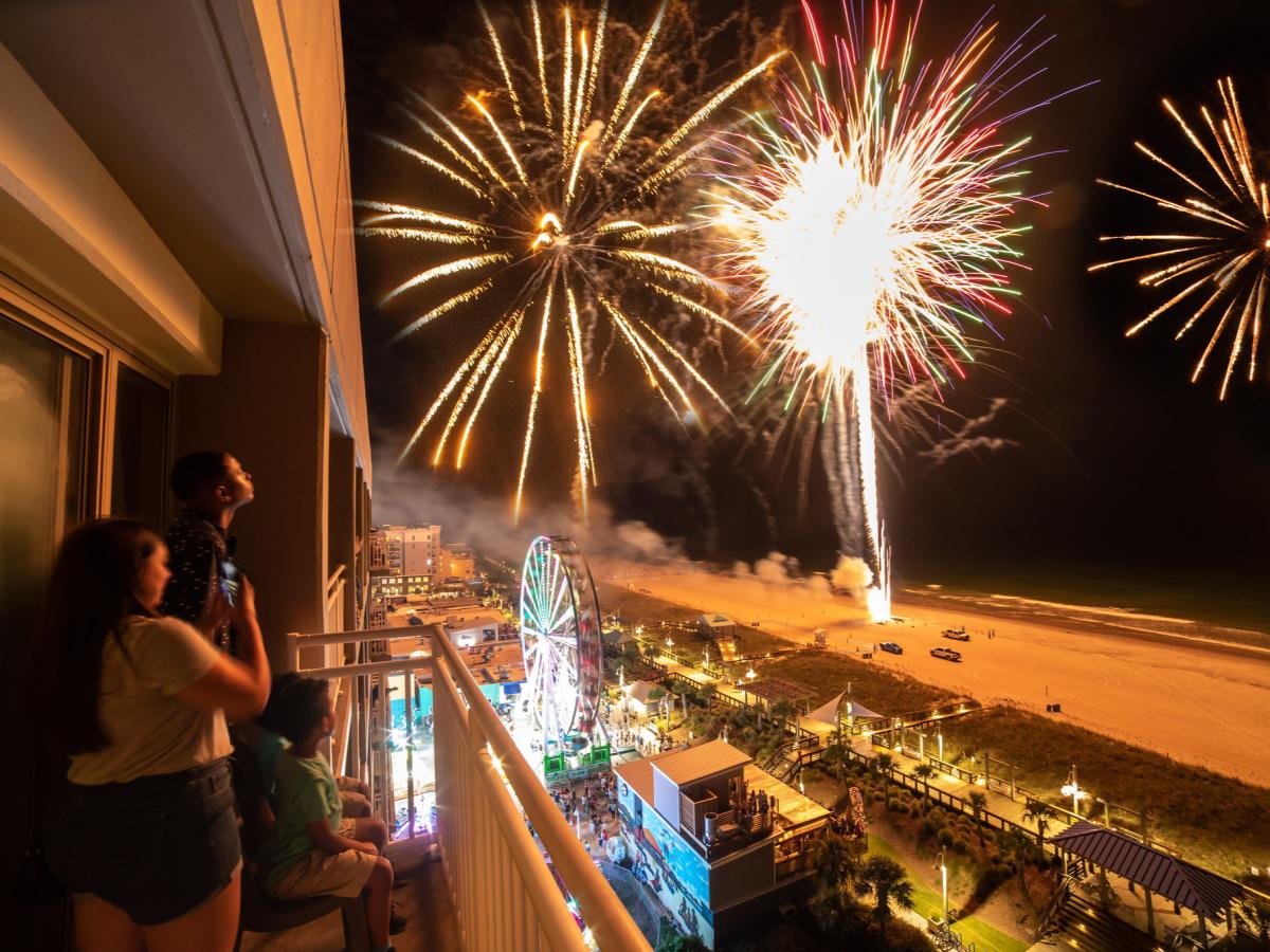 Family watching fireworks from balcony during Boardwalk Blast in Carolina Beach