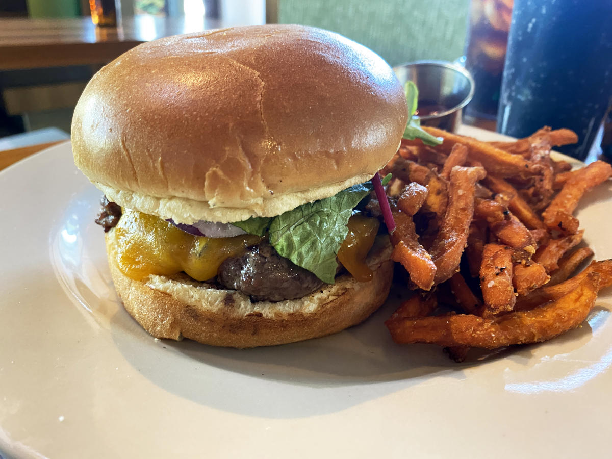 Cheeseburger and sweet potato fries on a white plate