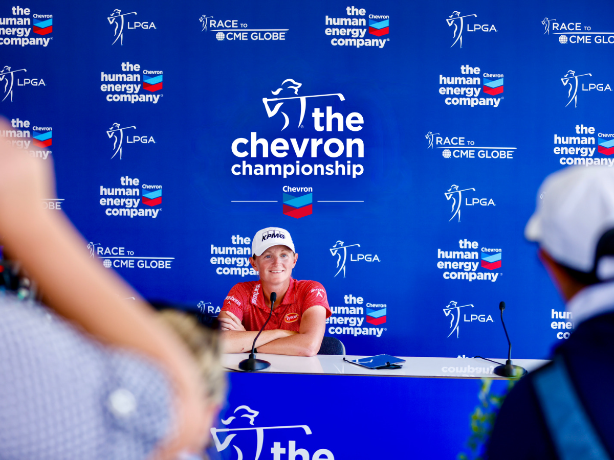 Woman sitting in front of The Chevron Championship sign