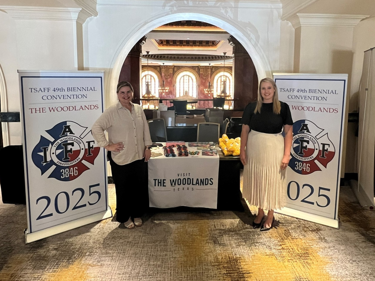 Elizabeth Eddins and Josie Lewis standing by Visit The Woodlands booth at The Texas State Association of Fire Fighters Bi-Annual Conference in El Paso, July 2023