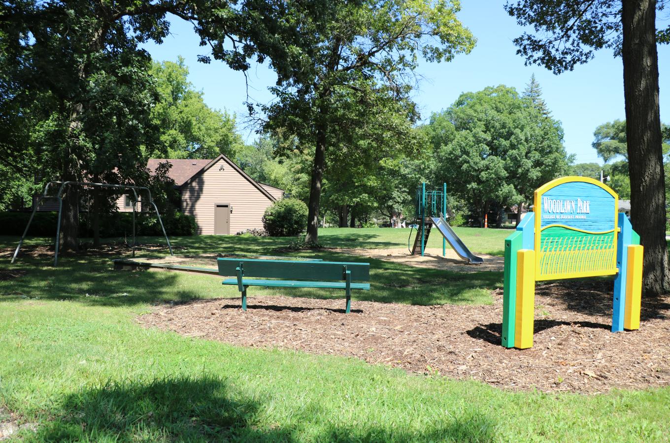 Woodlawn Park Sign with playground equipment in back V Pic