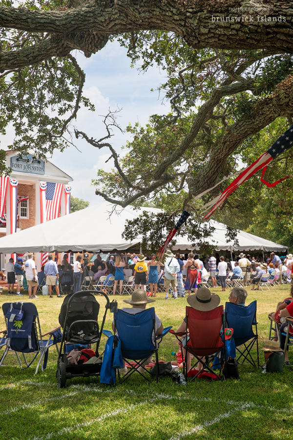 a group of people watching a ceremony under an outdoor tent in Southport for the NC 4th of July Festival