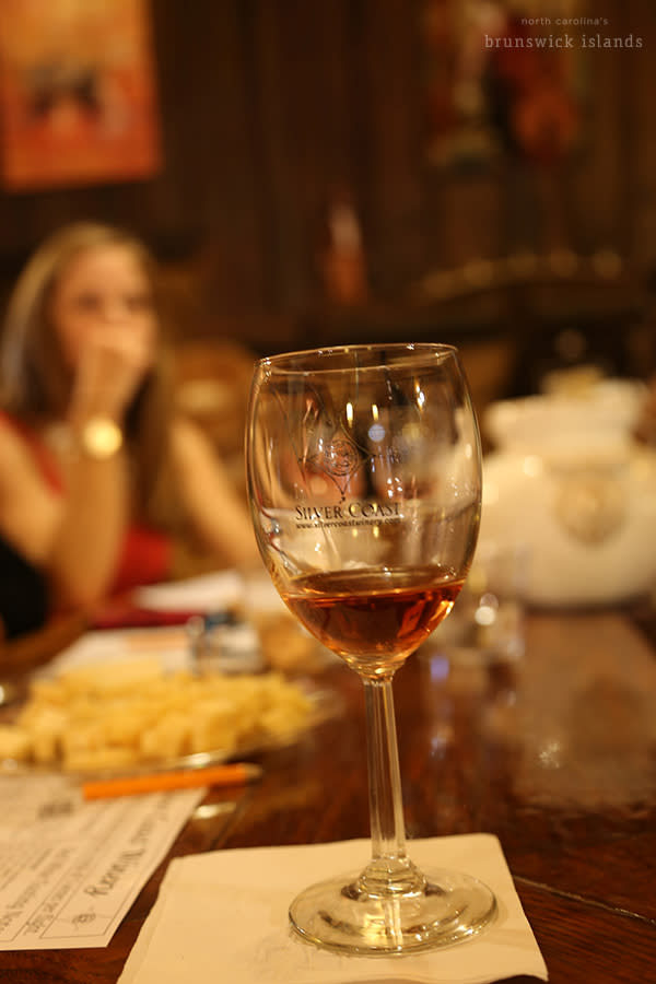 a wine glass filled with a sip of wine at a wine tasting at Silver Coast Winery in Ocean Isle Beach