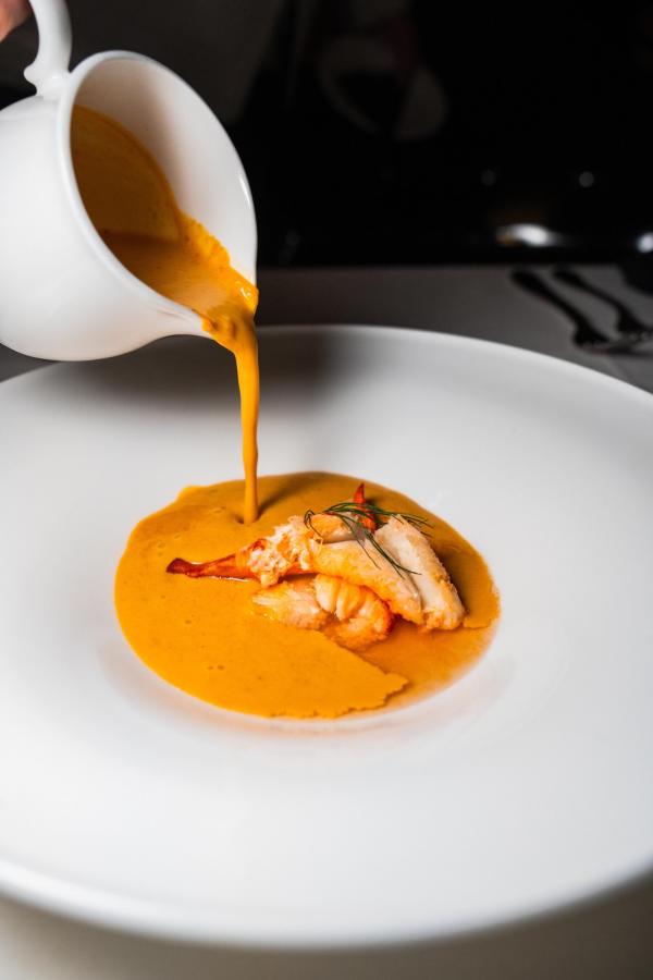 person pours bisque into bowl at Bridgeman's Chophouse