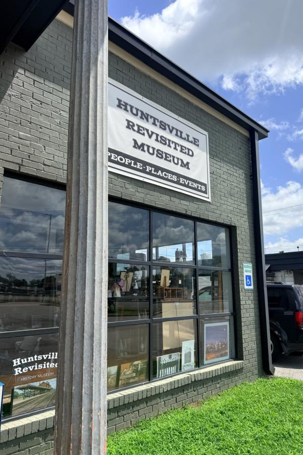 Exterior of the Huntsville Revisited Museum, featuring its sign above large front windows on a sunny day.