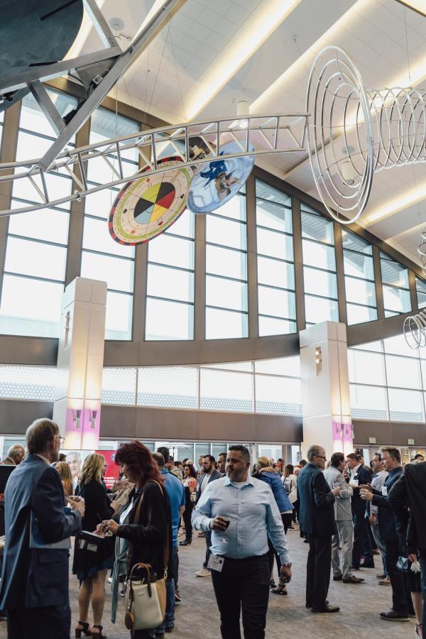 people standing beneath hanging art pieces inside of the convention center