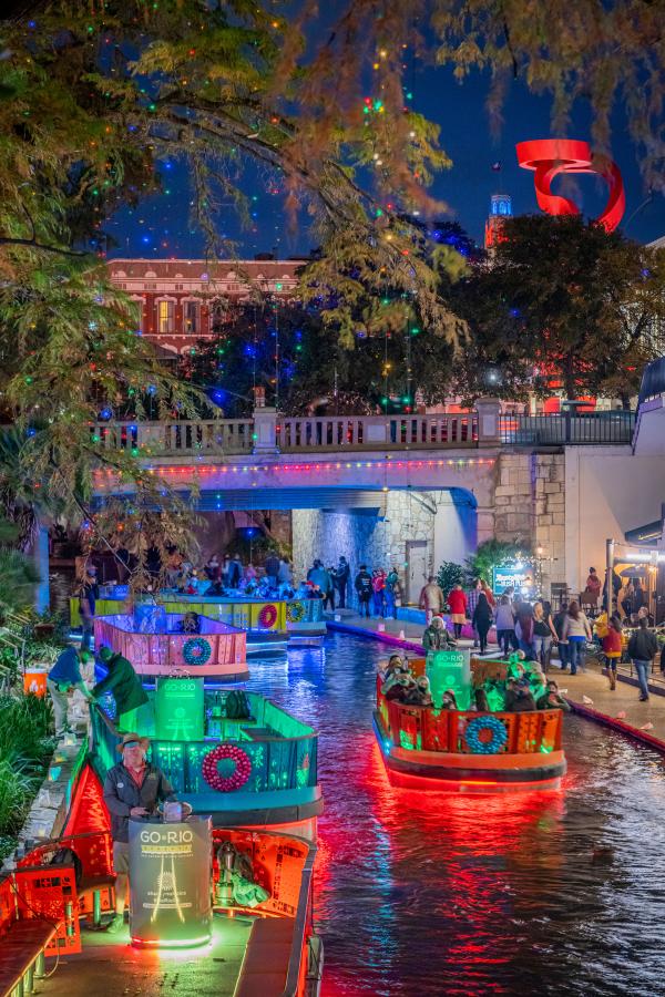 River Walk lit up with holiday lights and river barges
