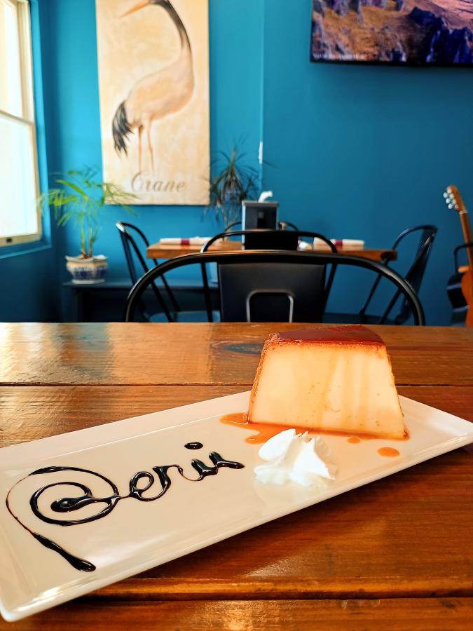 a plate of flan with Peru spelled out in chocolate syrup at Aromas at the Beach in Sunset Beach