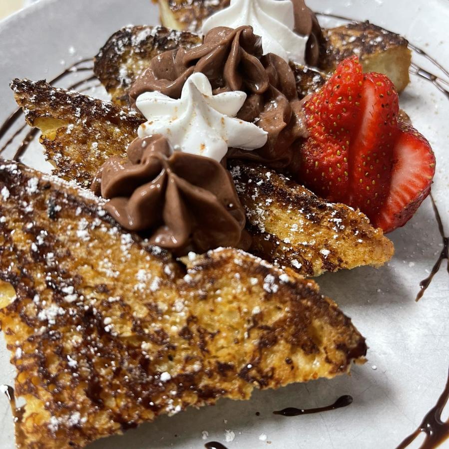 a plate of french toast decorated with chocolate whipped cream and strawberries from New Day Cafe in Leland
