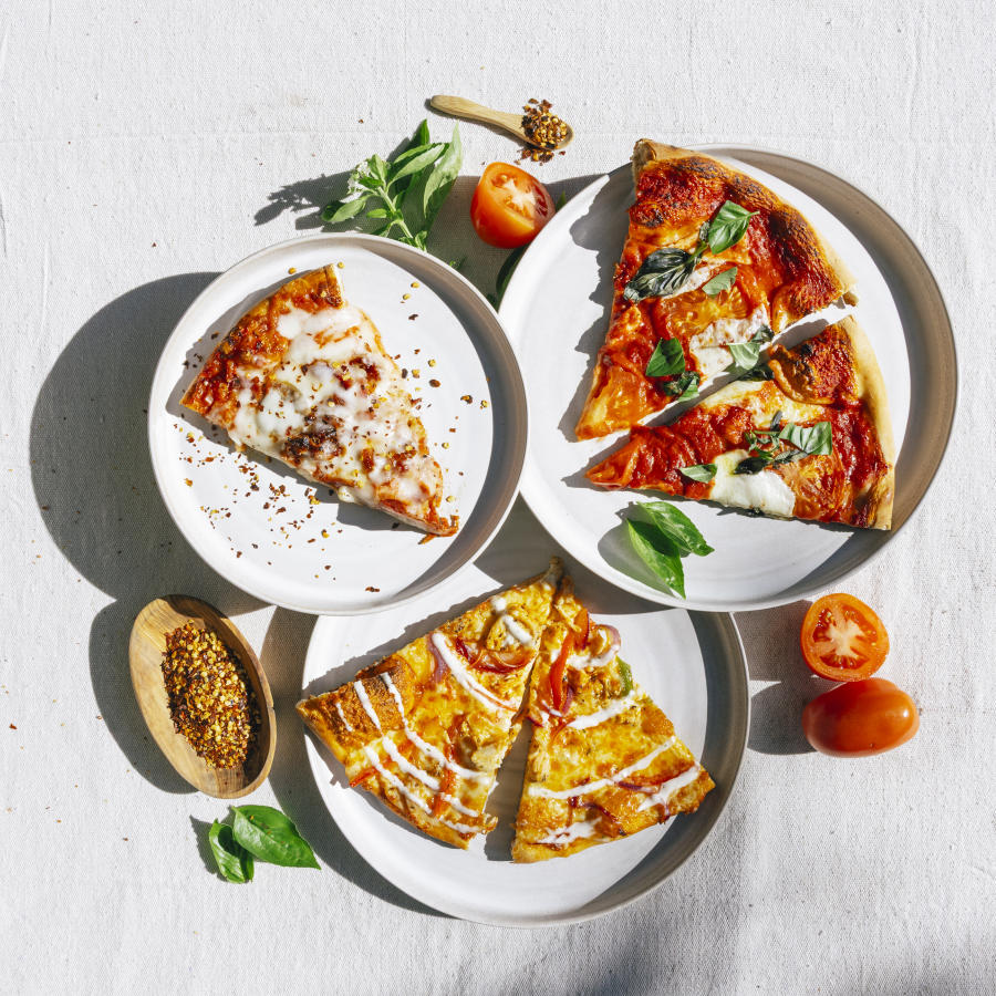 three white plates with 3 different kinds of pizza slices on each