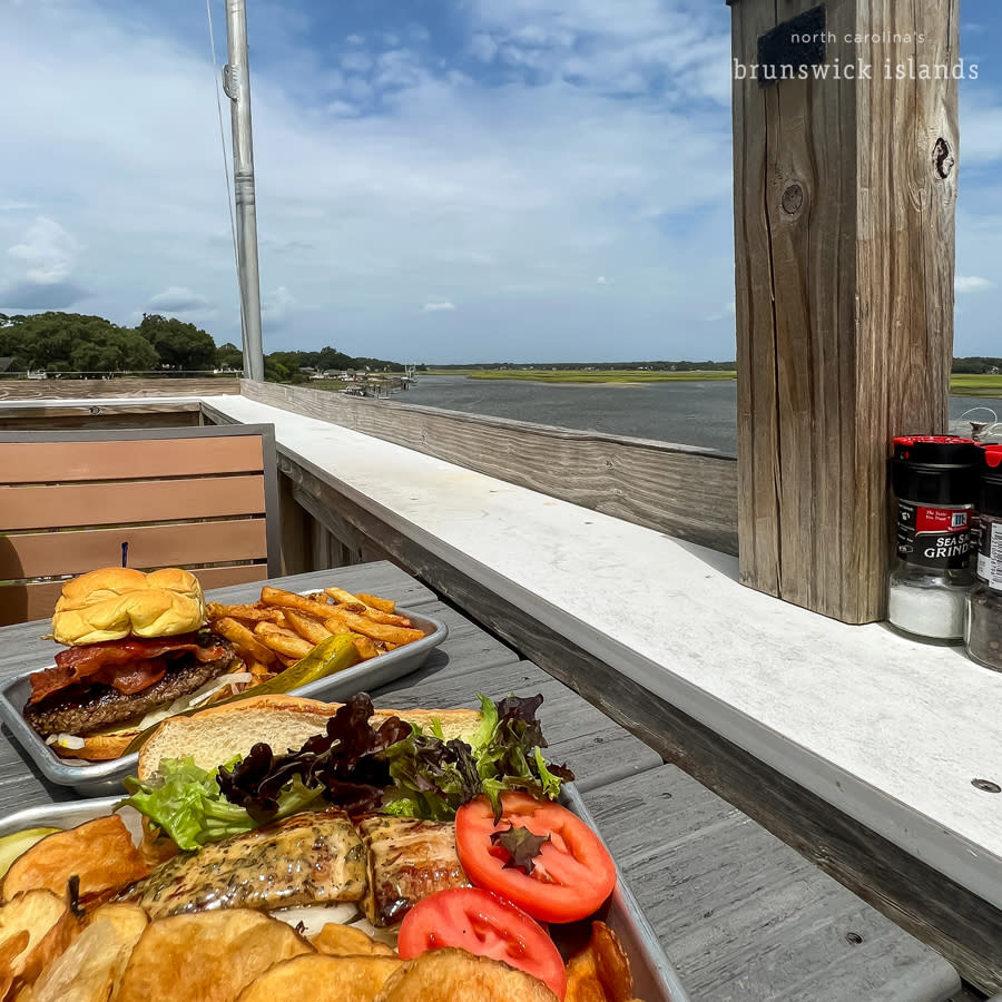 a view of a plate of food at a table outdoors at a waterfront restaurant
