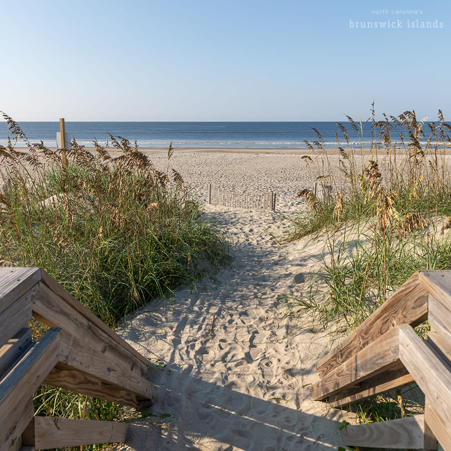 a walkway ending at the beach with a view of the ocean