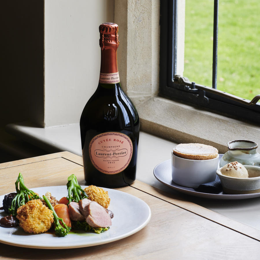 A colourful plate of food and a bottle of champagne by a window at The Slaughters Country Inn