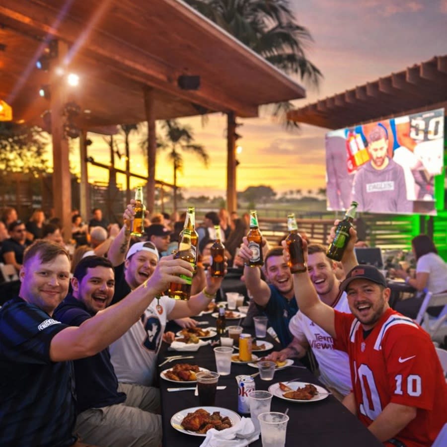 A group of men toasting to the photographer while dining outdoors at Galuppi's in Pompano Beach at sunset.